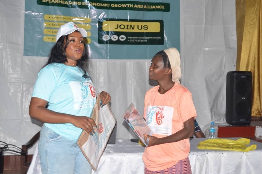 A woman receiving her certificate from a Wealth Trust facilitator